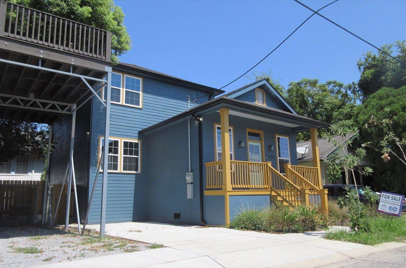 Two-story blue house with a for-sale sign in the front yard