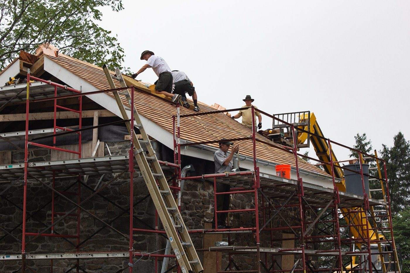 Crew on scaffolding re-roofing a stone house under renovation