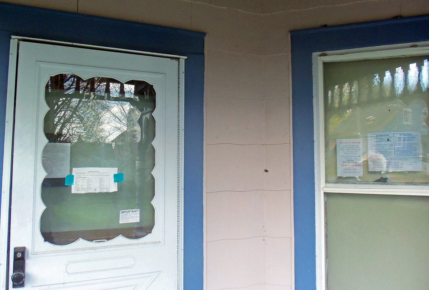 Front door of a vacant house with legal notices taped to the windows